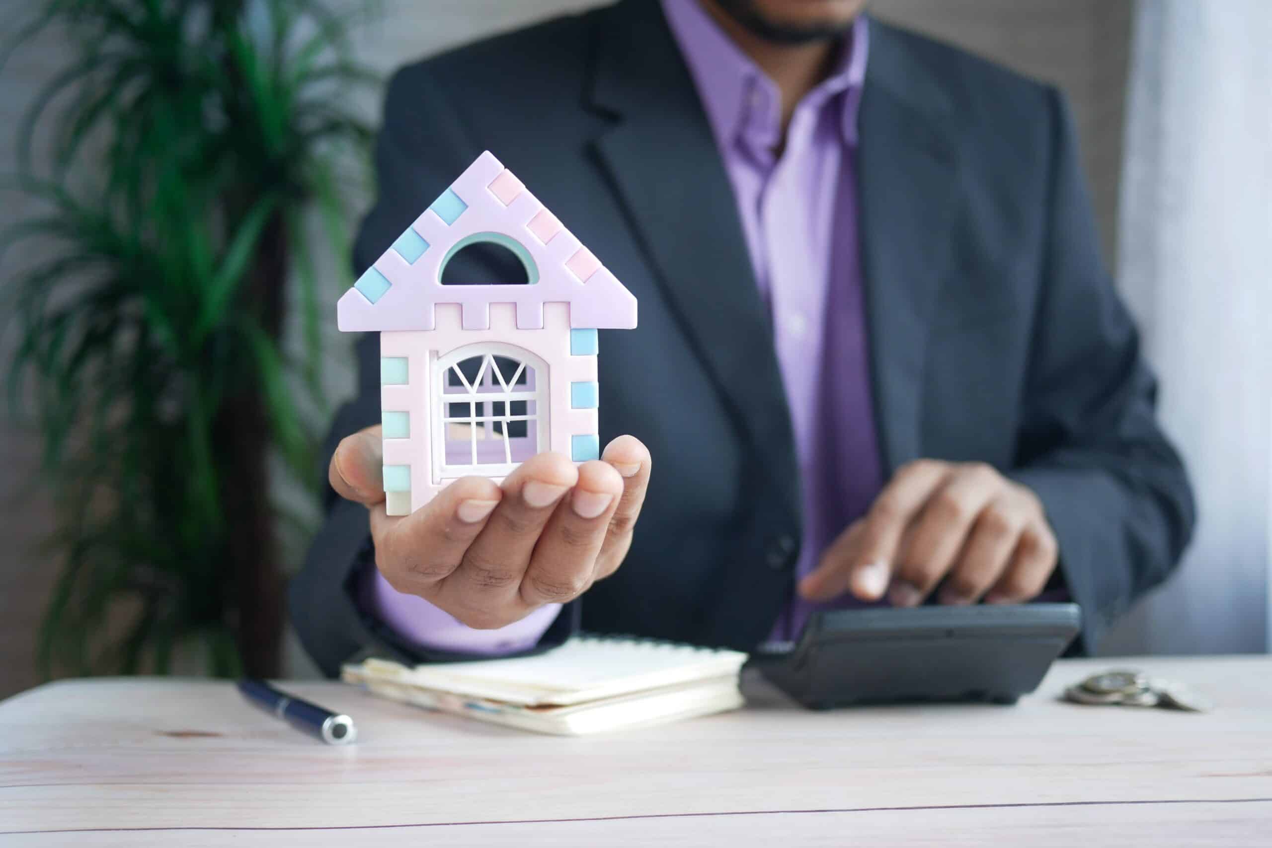 a man holding a small model of a house