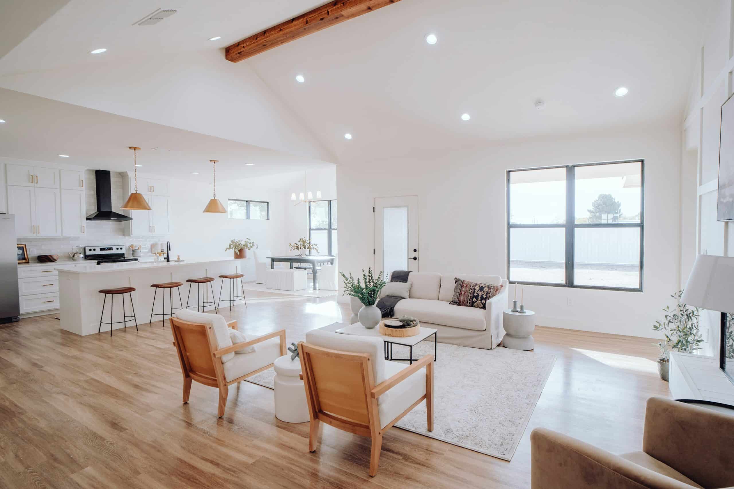 A spacious open-concept living area featuring a modern kitchen, cosy seating, and natural light from large windows.